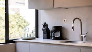 Een moderne keuken met een koffiezetapparaat, messenstel en een glazen karaf op het aanrecht.