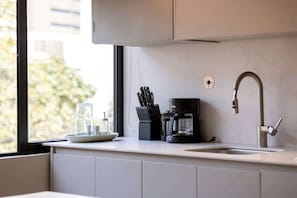 Eine moderne Küche mit einer Kaffeemaschine, einem Messerset und einem Glasbehälter auf der Arbeitsfläche.