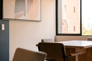 A modern office space with a large window, a framed abstract artwork, and a wooden table with chairs.
