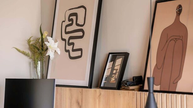 Een receptiegedeelte met een flatscreen-tv, een vaas met bloemen, ingelijste kunstwerken en een houten receptiebalie.