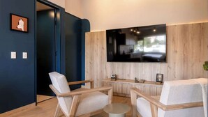 Een moderne woonkamer met een grote flatscreen televisie aan de muur, houten meubels en een kleine ronde tafel.