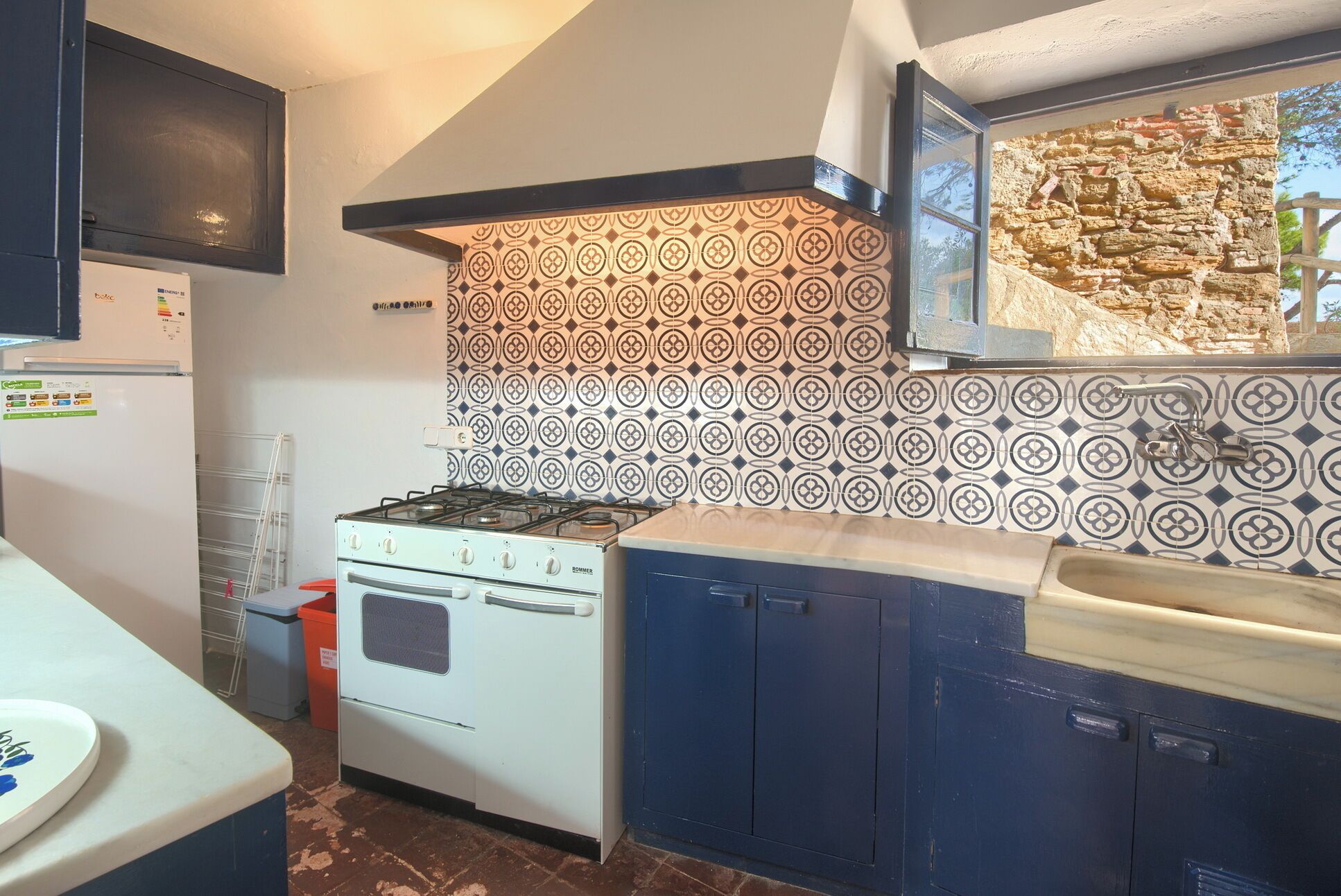 A kitchen with a gas stove, a refrigerator, and patterned backsplash tiles.