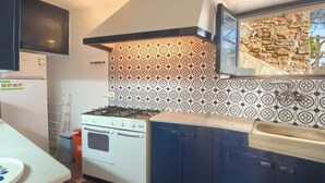 A kitchen with a gas stove, a refrigerator, and patterned backsplash tiles. - 3 bedroom in first sea line in Sa Tuna, Begur H02 (Begur)