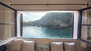 A window seat with cushions and a view of a coastal landscape. - 3 bedroom in first sea line in Sa Tuna, Begur H02 (Begur)