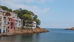 A coastal building with multiple balconies and a rocky shoreline. - 3 bedroom in first sea line in Sa Tuna, Begur H02 (Begur)