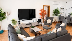 A modern living room with a sofa, chairs, a coffee table, a TV, and potted plants. - Villa w/ pool in Begur (H14) (Begur)