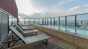 Zona de piscina en la azotea con sillones y vistas a la ciudad.