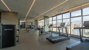 Un gimnasio con cintas de correr, bicicletas estáticas y máquinas de pesas.