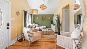 A modern living room with a sofa set, wooden flooring, and a large mirror. - Boho 5BR Modern Villa•Hot Tub•Grill•Patio•Backyard (Raleigh)