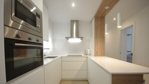 A modern kitchen with built-in appliances, a wooden accent wall, and a clean, minimalist design. - 30 - Livingtarifa El Poniente (Tarifa)