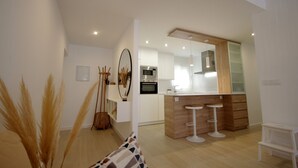 A modern kitchen with white cabinets, a wooden island, and two white bar stools. - 30 - Livingtarifa El Poniente (Tarifa)