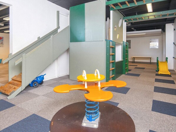 A children's play area with a seesaw, a slide, and a climbing structure.
