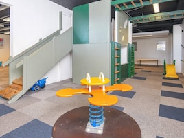 A children's play area with a seesaw, a slide, and a climbing structure.
