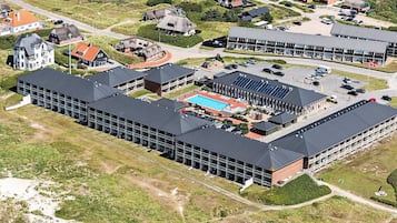 An aerial view of a hotel complex with multiple buildings, a swimming pool, and a parking area.
