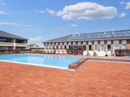 A swimming pool with lounge chairs and a building with solar panels.