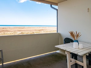 A balcony with a view of the beach, a table with a vase and a chair, and a wall with a small sign. - Inviting Holiday Home in Fano (Fano)