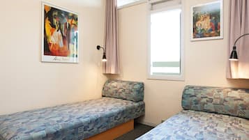Una habitación con dos camas, una ventana y dos cuadros en las paredes.