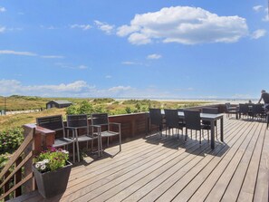 A wooden deck with outdoor seating, overlooking a beach and dunes. - 4 Person Holiday Park Home in Fano (Fano)