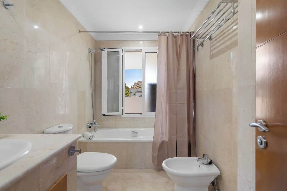 Un bagno con vasca, due servizi igienici, un lavandino e una finestra vista.