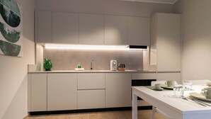 Eine moderne Küche mit weißen Schränken, einer Arbeitsplatte und einem Essbereich mit Tisch für zwei Personen.