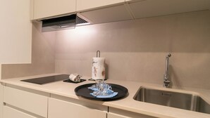 A kitchen with a stainless steel sink, a paper towel holder, and a glass with a utensil.