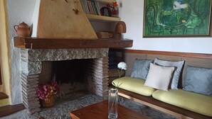 A cozy living room with a stone fireplace, a sofa with cushions, a wooden coffee table, and a painting on the wall. - Domos De Badas - Trilocale (Porto Ottiolu)