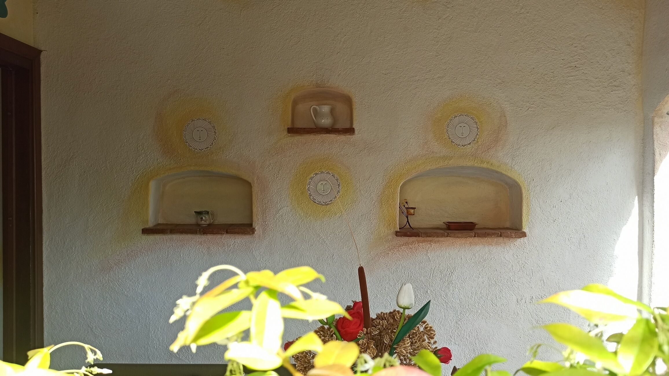 A wall with three small, arched niches, each containing a small object.