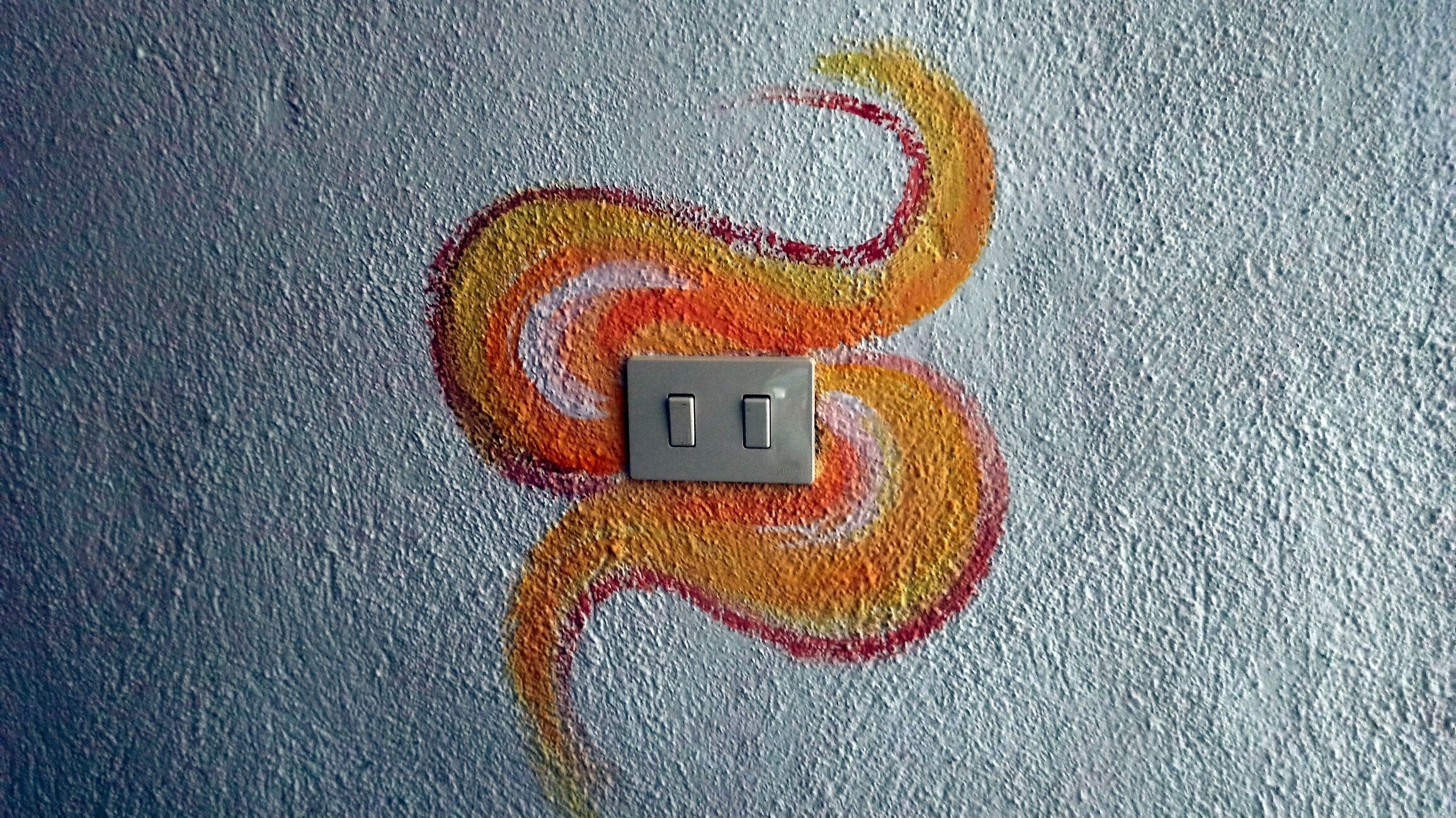 Un muro con una presa di corrente e un decorativo dipinto colorato.