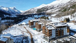 A snow-covered mountain resort with modern buildings, a swimming pool, and a ski slope. - Wifi, swimming pool, sauna, hammam, balcony, tv, ski locker, 44-53m², Serre Chevalier (La Salle-les-Alpes)