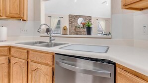 Una cocina moderna con armarios de madera, lavavajillas de acero inoxidable y un espejo grande sobre el fregadero.