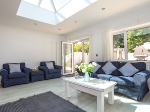 A spacious living room with two sofas, a coffee table, and a skylight. - Awel Y Mor (Pwllheli)