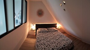 A bedroom with a bed, bedside lamps, a wall-mounted light fixture, and a window. - Chambre en Brière with jacuzzi near Guérande (Saint-Lyphard)