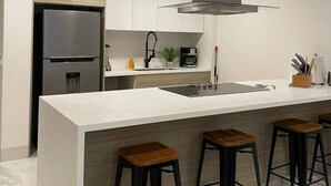 A modern kitchen with a large island, stainless steel appliances, and bar stools.