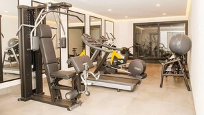 A modern gym with various exercise equipment, including a bench press, a treadmill, and a stationary bike.