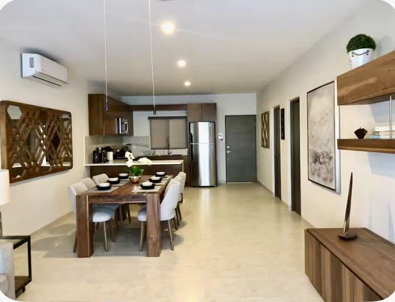A modern kitchen with a dining area, a built-in oven, and a refrigerator.