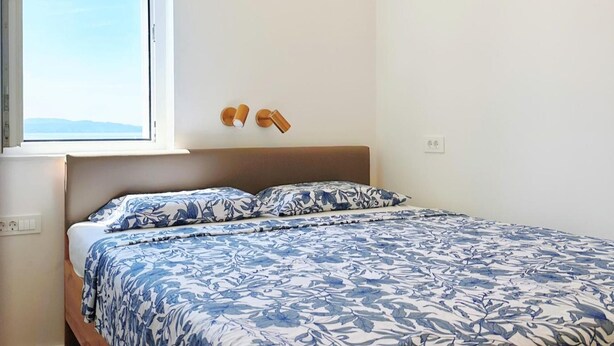 A bedroom with a bed, a window, and a wall-mounted light fixture. - Sea View Apartment Rijeka-free Parking-6 People (Rijeka)