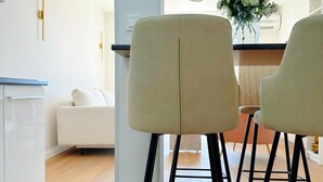 A modern kitchen with a white countertop, two bar stools, and a white sofa in the background. - Sea View Apartment Rijeka-free Parking-6 People (Rijeka)