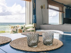 A room with a view of the ocean, a table with woven placemats, and a sofa. - 4 Person Holiday Home in Martofte (Martofte)