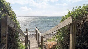 Un sentier en bois mène à une plage d’où l’on a une vue dégagée sur la mer.