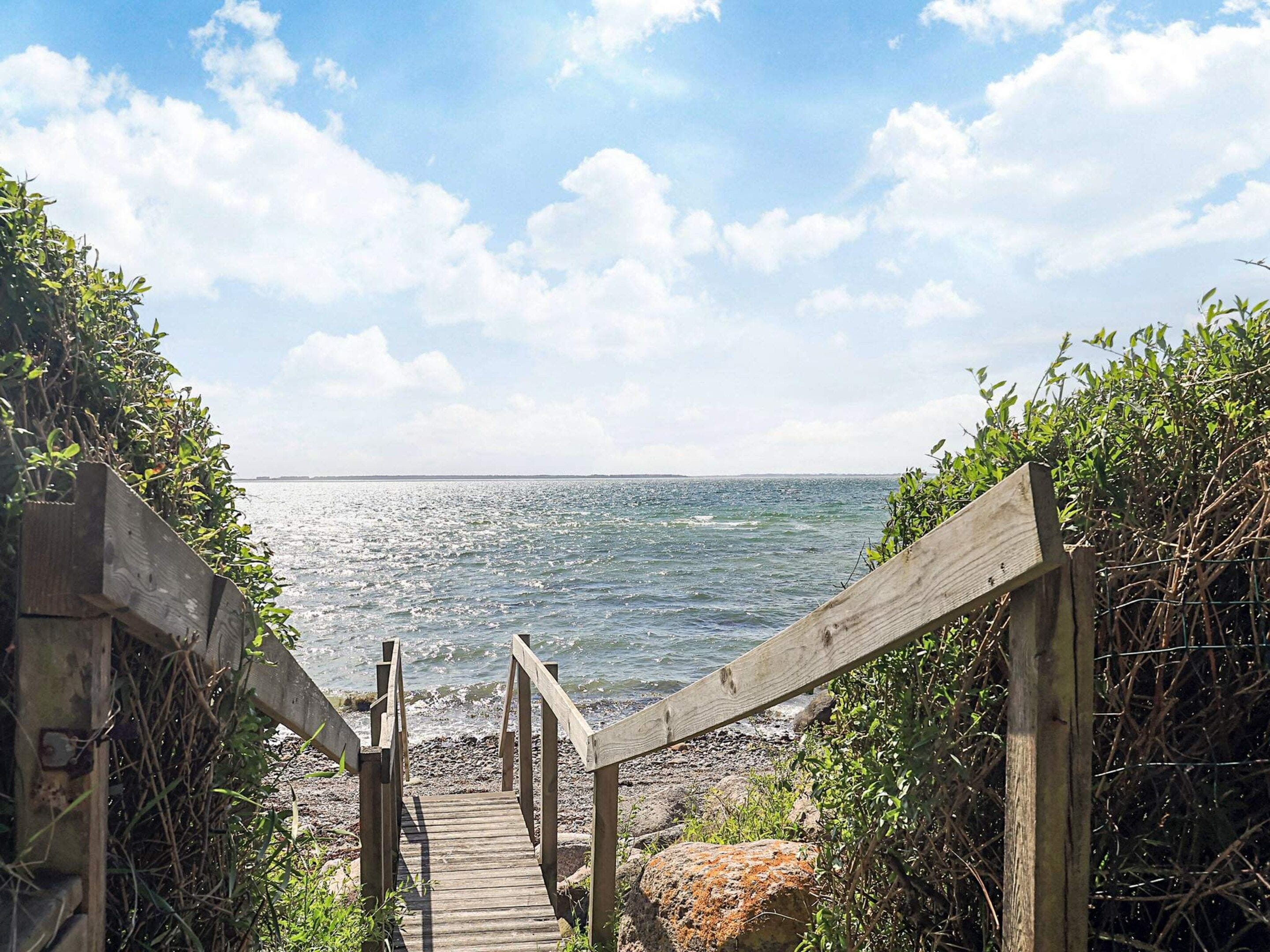 A wooden staircase leading to a beach with a clear sky and calm sea.
