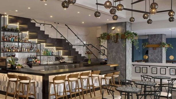 Un área de bar moderna con mostrador, taburetes y una escalera.