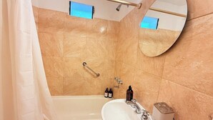 Een badkamer met een bad, wastafel, spiegel en toiletartikelen.