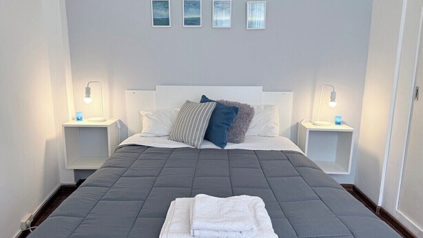 Een hotelkamer met een groot bed, twee nachtkastjes en een hoofdeinde.