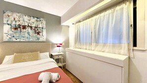 A hotel room with a bed, a bedside table, a lamp, a window with curtains, and a painting on the wall. - Charming Studio in Palermo Chico · Fast Wi-Fi (Palermo)