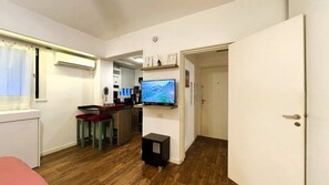 A compact living space with a kitchenette, a television, and a door leading to another room.