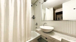 A bathroom with a bathtub, a sink, a mirror, and a shower curtain.