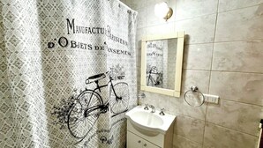A bathroom with a patterned shower curtain, a sink, and a mirror.
