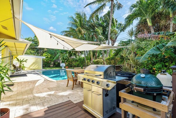 A backyard with a pool, a grill, and a barbecue area.
