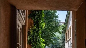 An indoor corridor with a view of an outdoor path, surrounded by greenery and buildings. - Lovely cozy studio - Pentes of Croix Rousse (Lyon)