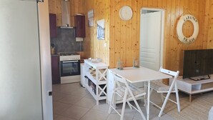 Une cuisine compacte équipée d’une cuisinière, d’un four et d’un petit coin repas avec une table et des chaises.